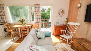 Una sala de estar acogedora con sofá, sillas, una mecedora de madera, una mesa de comedor y vistas al exterior.