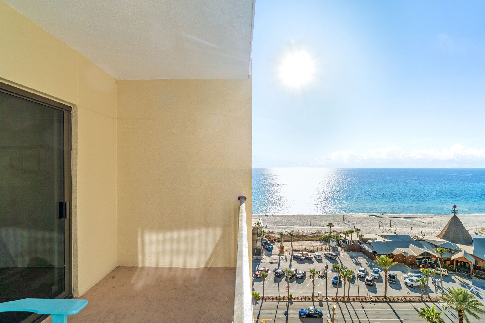 A balcony with a view of a beach and parking area.