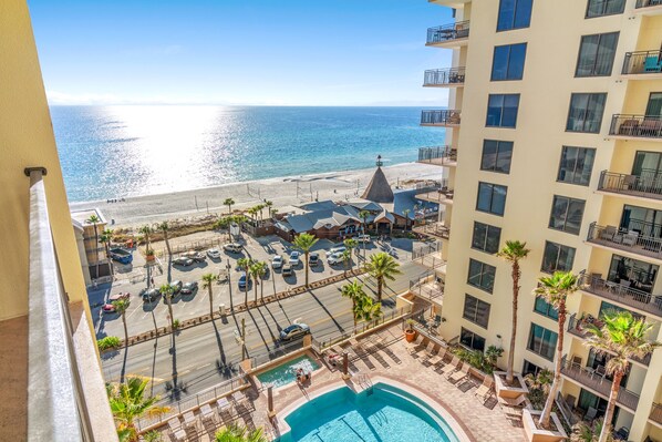 Ein Hochhaus-Hotel mit Pool, Blick auf den Strand und Parkplatz.