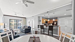 Ein modernes Wohnzimmer mit Esstisch, einer Couch und einer Küchenzeile mit Barhocker.