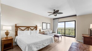 Une chambre d’hôtel avec un grand lit, un canapé, un bureau, un ventilateur de plafond et un balcon avec vue.
