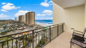 A balcony with a view of the ocean and cityscape, including tall buildings and a road with cars. - Origin 1129 - Efficiency Unit - Partial Gulf View (Panama City Beach)