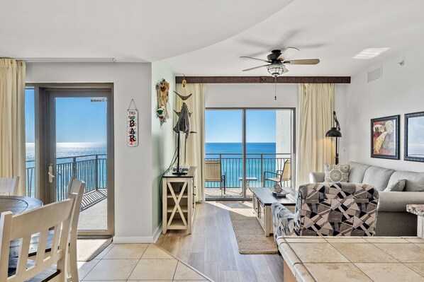 Uma sala de estar ampla com varanda vista para o mar, uma área de refeições com vista e um ventilador de teto.