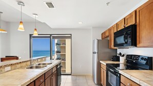 A modern kitchen with a large island, stainless steel appliances, and wooden cabinets.