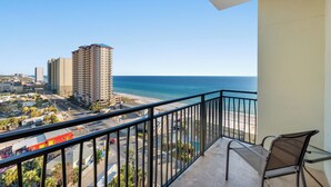 Un balcón con vistas al océano y al paisaje urbano, incluyendo edificios altos y una playa.