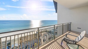 A balcony with a view of the ocean and beach, a chair, and a railing. - Origin 1235 - 2 Bedroom - Stunning Gulf Views (Panama City Beach)