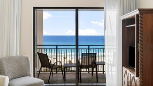 A balcony with a view of the ocean, a chair, a table, and a TV stand. - Origin 0601/603 - Two Bedroom Lock Out with Sunset and Gulf Views (Panama City Beach)