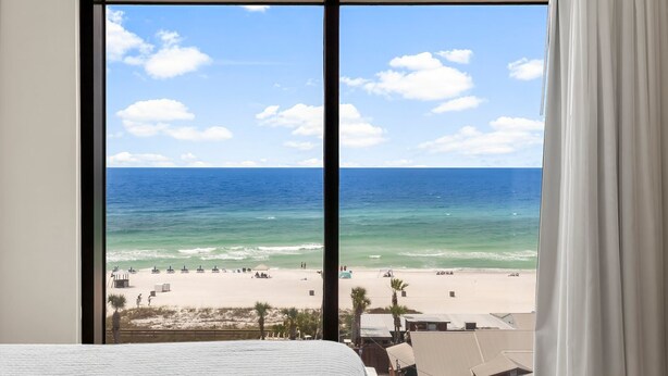 A large window with a view of a beach and ocean. - Origin 0601/603 - Two Bedroom Lock Out with Sunset and Gulf Views (Panama City Beach)