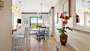 A dining area with a table and chairs, a potted plant, and a view of the outdoors.
