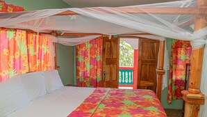 A room with a bed, a wooden door, and a balcony with a view. - Haley's Paradise at Blue Hole (Little Bay)