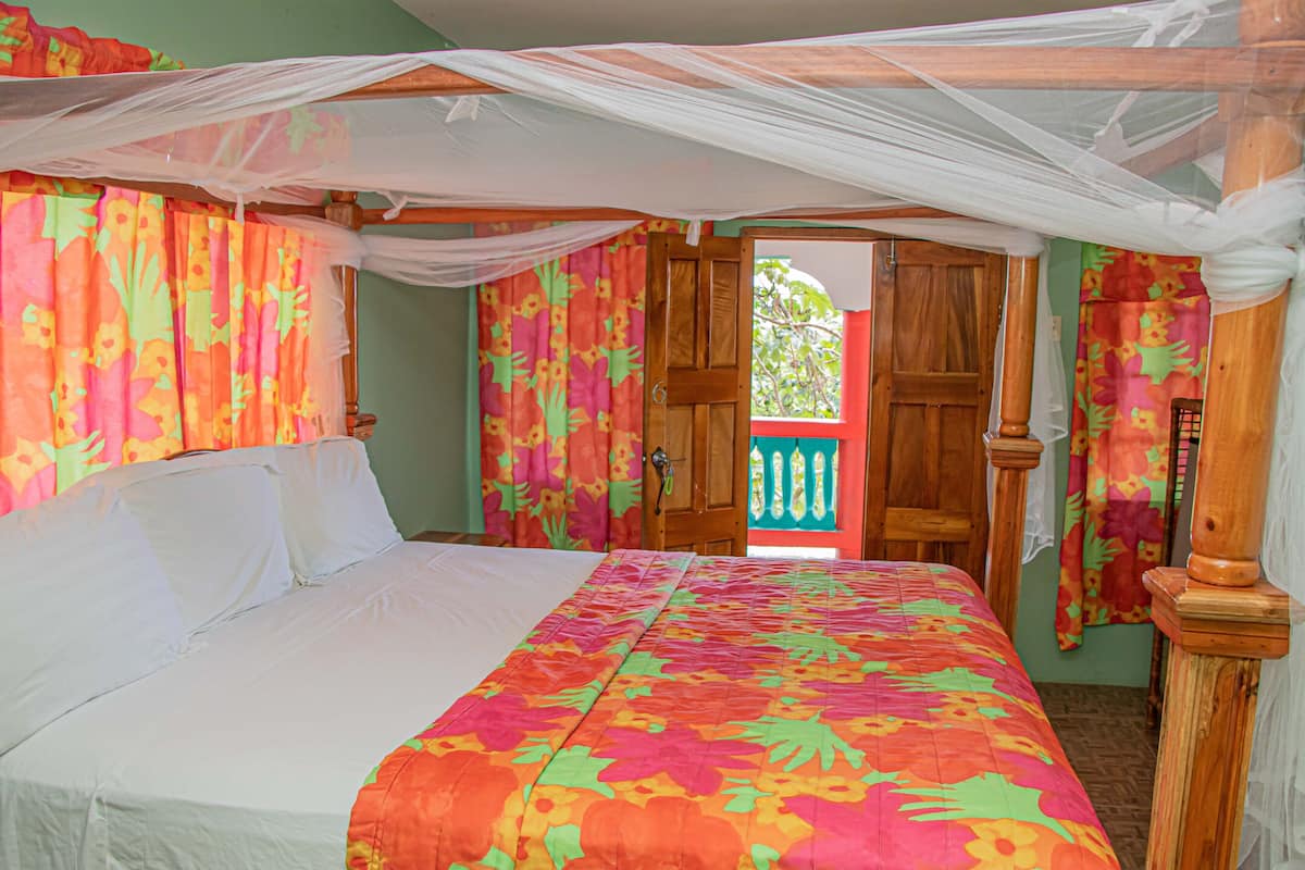 Een kamer met een bed, een houten deur en een balkon met uitzicht.