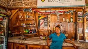 A bar area with a wooden interior, a sign reading "BLUE HOLE Mineral Spring Brighton, Jamaica", and various bottles and decorations. - Haley's Paradise at Blue Hole (Little Bay)