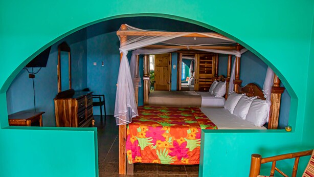 A room with a bed under a canopy, a desk, and a chair. - Haley's Paradise at Blue Hole (Little Bay)