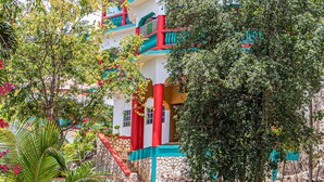 A multi-story building with balconies, surrounded by greenery and trees. - Haley's Paradise at Blue Hole (Little Bay)