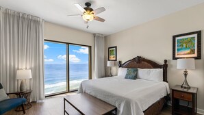 A hotel room with a large bed, a ceiling fan, a view of the ocean, and a beach-themed painting on the wall. - Origin 1333/1335 - Three Bedroom Gulf View Connector Unit- Stunning Gulf Views (Panama City Beach)