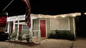 Ein Haus mit roter Tür, einer kleinen Veranda und einem Fahnenmast mit der US-amerikanischen Flagge.
