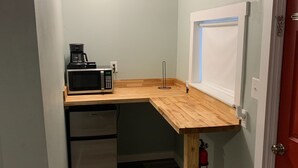Eine kleine Küche mit Mikrowelle, Kaffeemaschine und kleinem Kühlschrank.