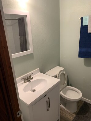 A bathroom with a white sink, a mirror, a toilet, and a towel rack.