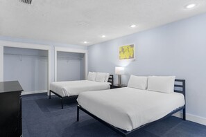 Ein Hotelzimmer mit zwei Betten, einem Schreibtisch und einem Kleiderschrank.