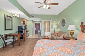 Une chambre d’hôtel équipée d’un lit, d’un bureau, d’une chaise, d’un canapé, d’une lampe et d’un ventilateur de plafond.