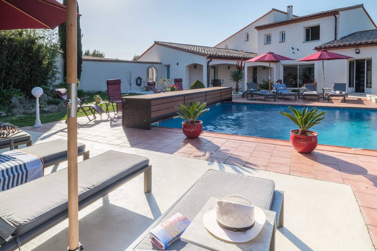 A poolside area with lounge chairs, a bar, and potted plants.