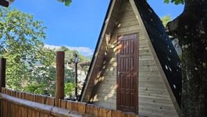 A wooden cabin with a pitched roof, a wooden door, and a wooden fence. - Raio de Sol Pousada & Camping (Angra dos Reis)