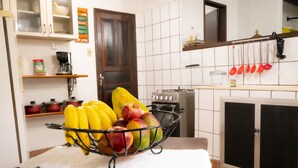 Una cocina con una cesta de frutas sobre la encimera, una estufa y diversos utensilios de cocina.