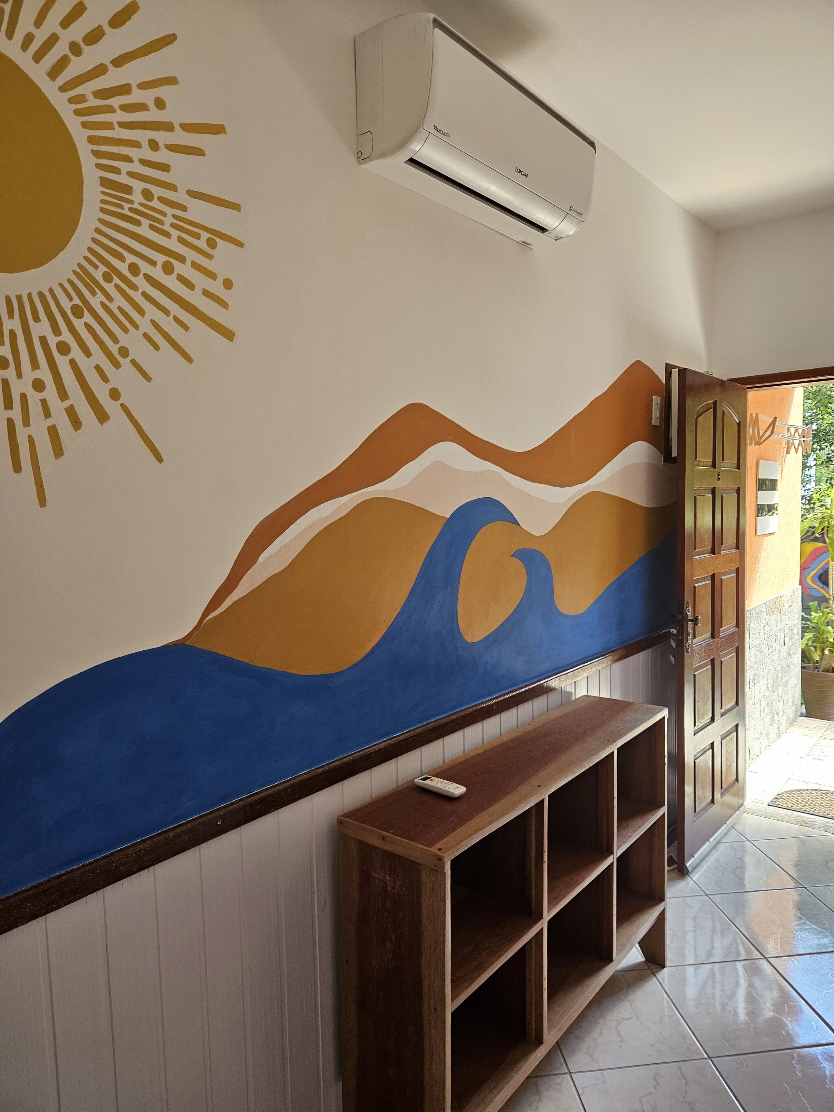 Un pasillo con un mural en la pared, un banco de madera y un equipo de aire acondicionado.