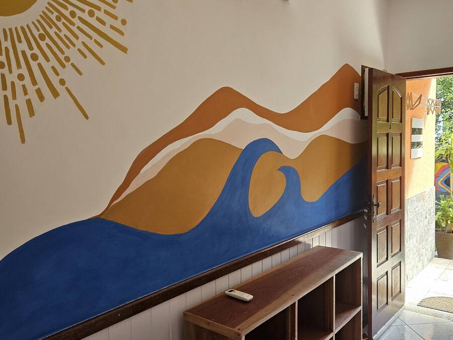 Un pasillo con un mural en la pared, un banco de madera y un equipo de aire acondicionado.