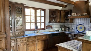 Eine traditionelle Küche mit Holzschränken, einer gefliesten Spritzschutzwand und einem großen Fenster.