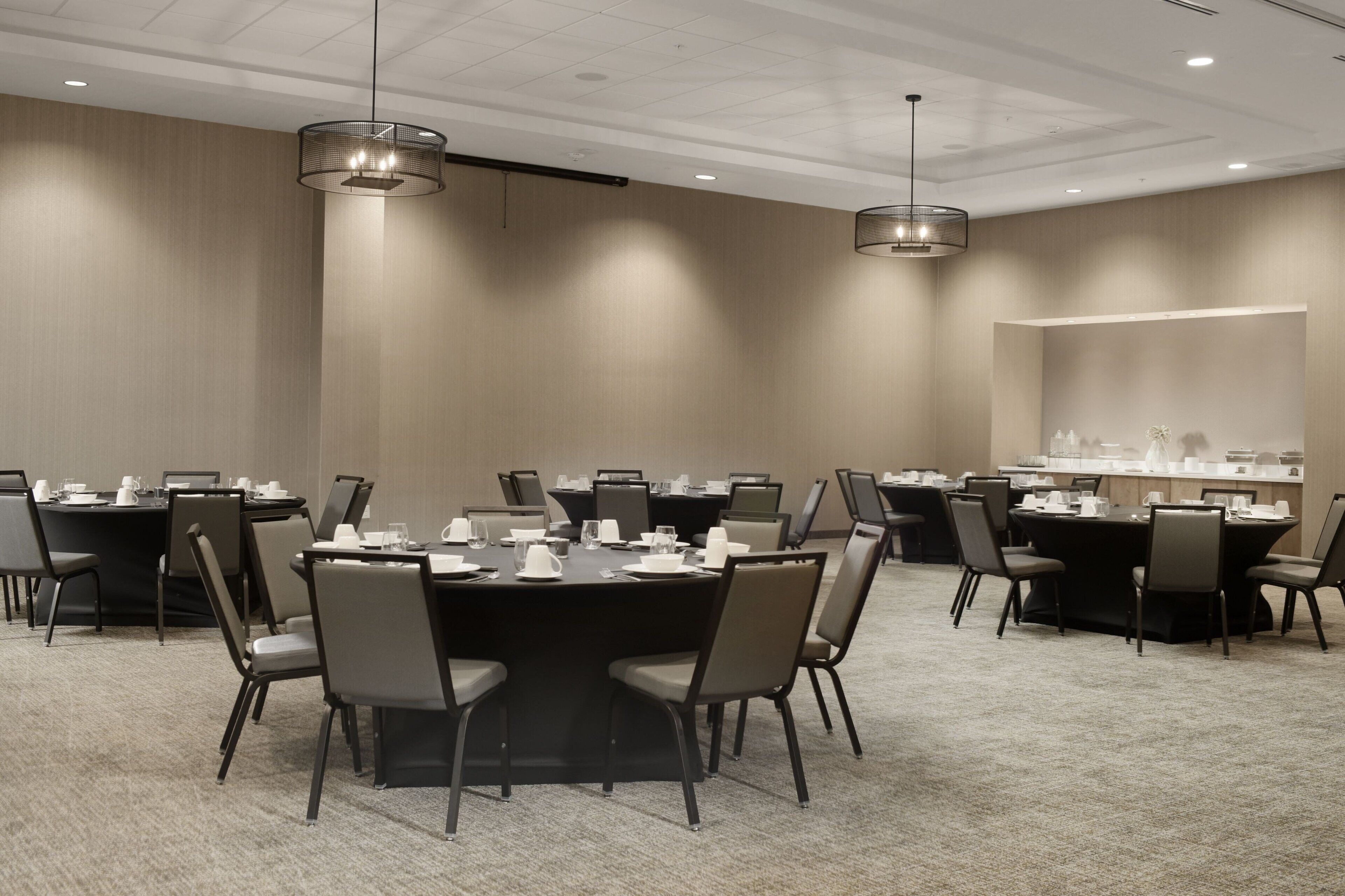 A conference room with multiple tables and chairs, equipped with laptops and various office supplies.