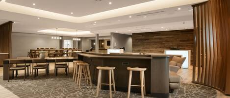 A modern hotel lobby with a bar area, seating, and a wooden accent wall.