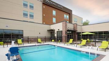 Een buitenzwembad, parasols bij het zwembad en ligstoelen