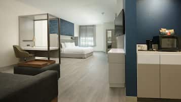 A modern hotel room with a bed, a desk with a chair, a TV, and a microwave.