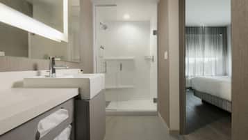A modern bathroom with a large mirror, a sink, and a shower area.