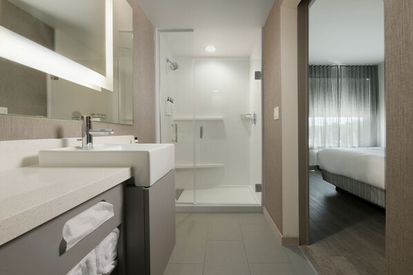 Un baño moderno con un espejo grande, un lavabo y una zona de ducha.