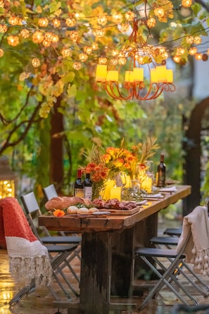 Un espace de restauration en plein air avec une table en bois rustique, des bougies et une guirlande lumineuse.