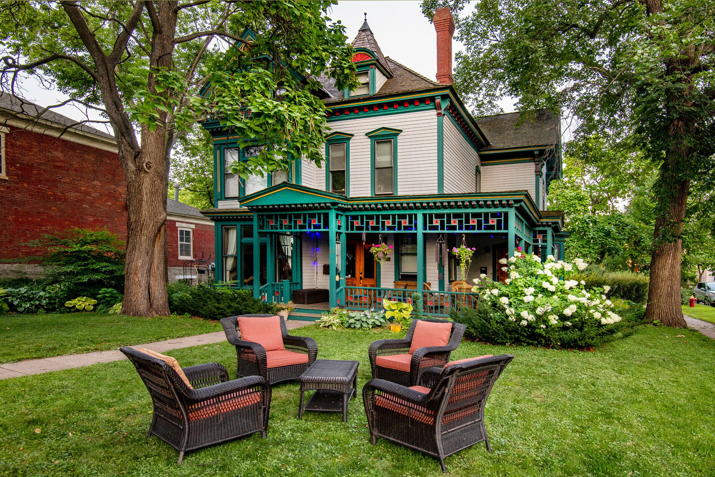 A Victorian-style house with a porch, green trim, and wicker furniture.
