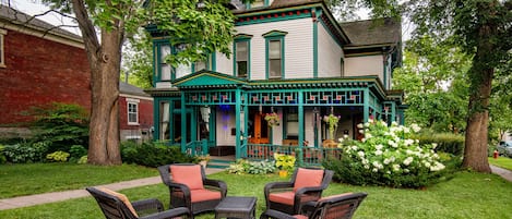 A Victorian-style house with a porch, green trim, and wicker furniture.