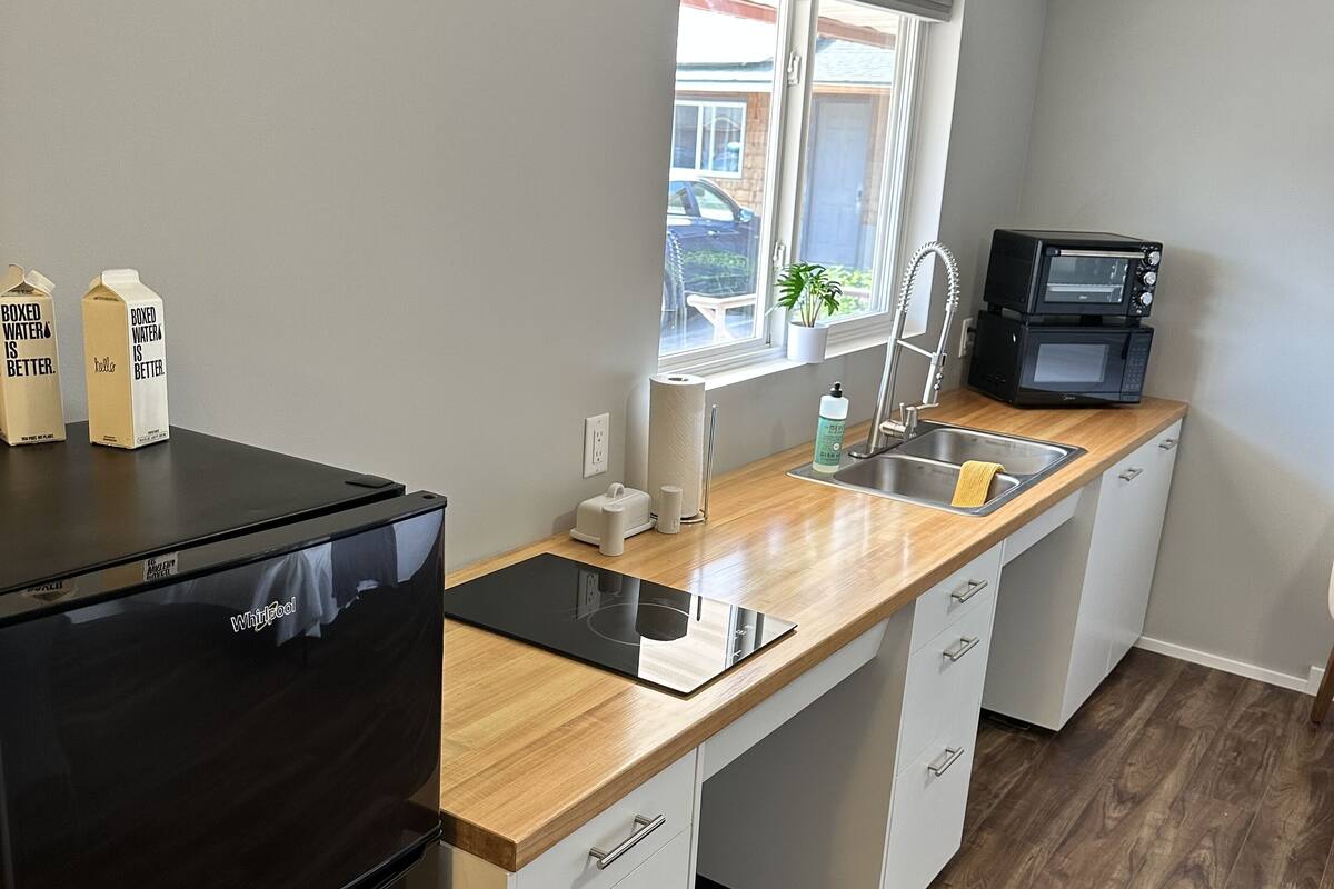 Une cuisine moderne avec un réfrigérateur noir, un four à micro-ondes encastré et un plan de travail en bois.