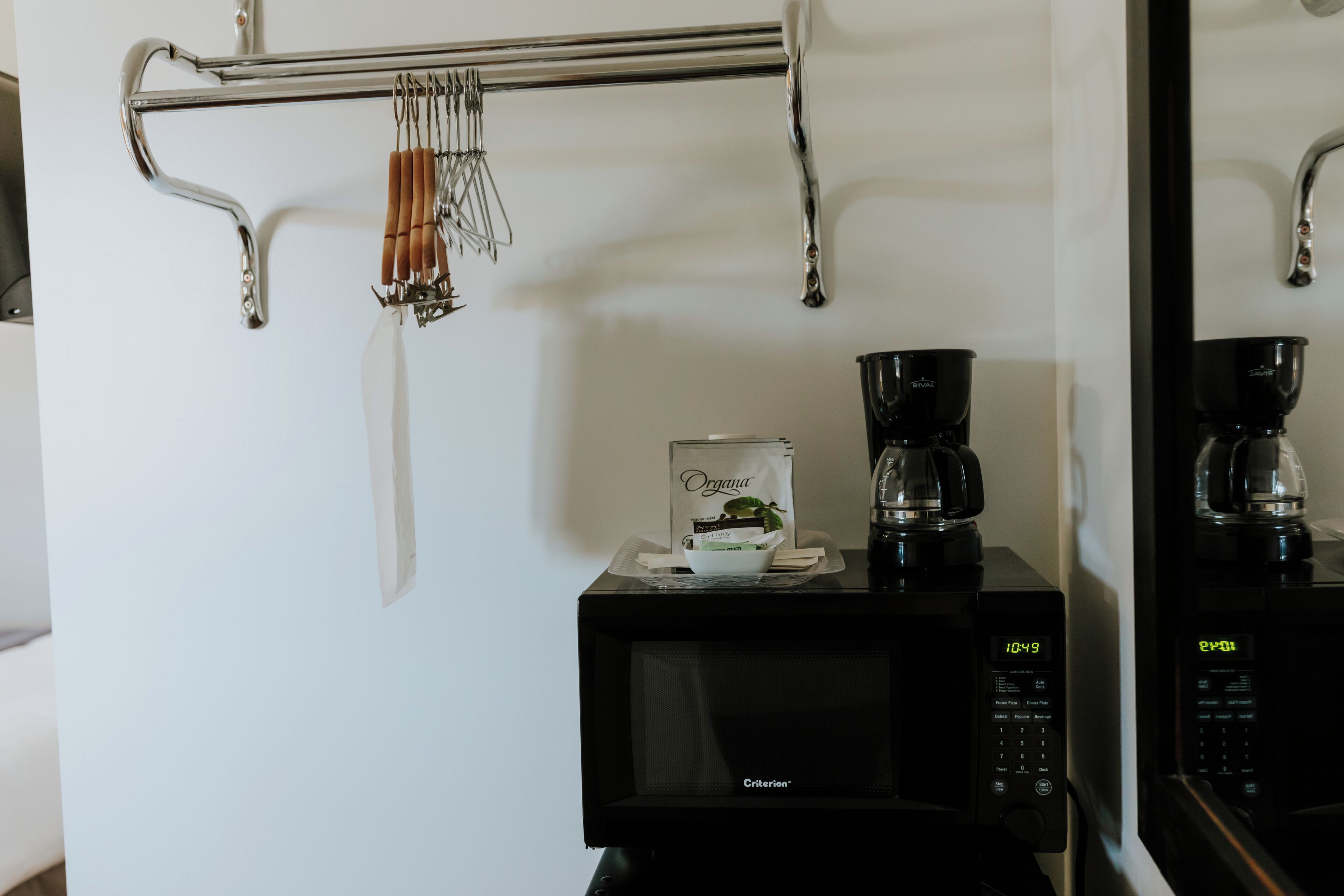 A kitchen area with a microwave, coffee maker, and hanging utensils.