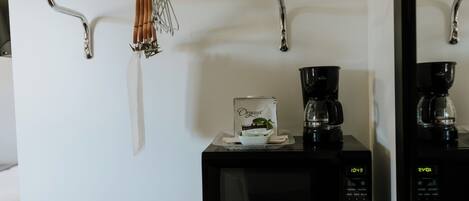 A kitchen area with a microwave, coffee maker, and hanging utensils.