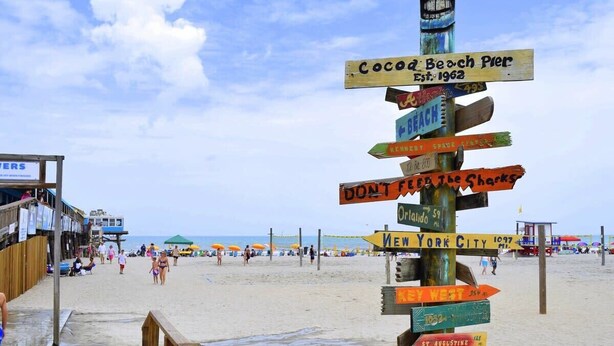 A beach with a wooden signpost with various directions and warnings. - 1BR Cocoa Beach Home - 1 Min to Beach! (Cocoa Beach)