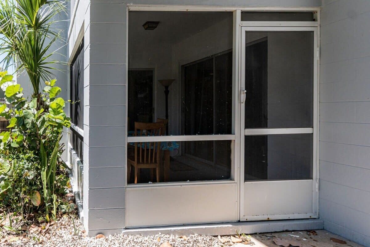 A building with a sliding glass door leading to an interior space with a table and chairs.
