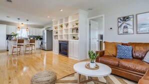 A spacious living room with a brown leather sofa, a white coffee table, and a fireplace.