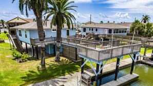 A waterfront property with elevated wooden decks, a swimming pool, and a small boat dock.