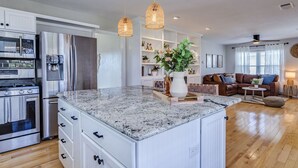 A modern kitchen with granite countertops, stainless steel appliances, and pendant lighting.