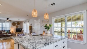 A spacious kitchen with a granite island, white cabinetry, and pendant lighting.