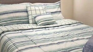 A bed with a striped bedspread and matching pillows. - Cozy Riverfront Retreat Close to City (Mableton)