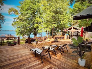 Una terraza de madera con mobiliario exterior, un pabellón y vistas al mar.